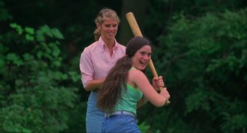 Movie still from “The Burning” (1981), directed by Tony Maylam – Two young women are playing a game of baseball; Medium shot, Over the shoulder angle