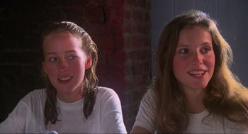 Movie still from “The Burning” (1981), directed by Tony Maylam – Two young girls sitting next to each other in front of a brick wall; Close Up shot, Over the shoulder angle