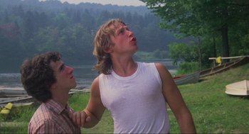 Movie still from “The Burning” (1981), directed by Tony Maylam – A man with long blonde hair is standing next to another man in a white shirt; Medium shot, Low angle