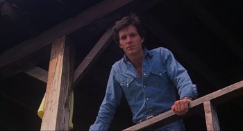 Movie still from “The Burning” (1981), directed by Tony Maylam – A man in a denim shirt leaning on a railing; Close Up shot, Low angle