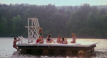 Movie still from “The Burning” (1981), directed by Tony Maylam – A group of women sitting on a dock next to a body of water; Extreme Wide shot, High angle