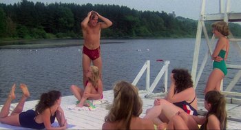 Movie still from “The Burning” (1981), directed by Tony Maylam – A group of people sitting and standing on a dock; Wide shot, Low angle