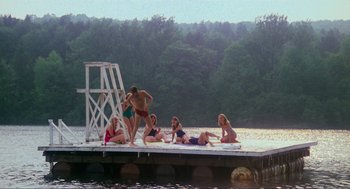 Movie still from “The Burning” (1981), directed by Tony Maylam – A group of people sitting and standing on a dock; Extreme Wide shot, High angle