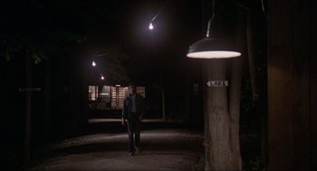 Movie still from “The Burning” (1981), directed by Tony Maylam – A man standing next to a tree in the dark at night; Wide shot, Low angle