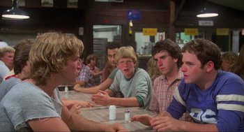 Movie still from “The Burning” (1981), directed by Tony Maylam – A group of young men sitting around a table; Medium shot, Over the shoulder angle