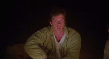 Movie still from “The Burning” (1981), directed by Tony Maylam – A man sitting in a dark room with his eyes wide open; Close Up shot, Low angle