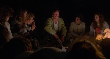 Movie still from “The Burning” (1981), directed by Tony Maylam – A group of people sitting on the ground in the dark; Medium shot, Over the shoulder angle