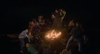 A group of people sitting around a fire pit at night