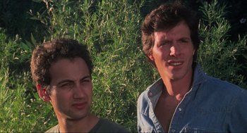 Movie still from “The Burning” (1981), directed by Tony Maylam – Two men standing next to each other in front of a bush; Close Up shot, Low angle