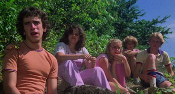Movie still from “The Burning” (1981), directed by Tony Maylam – A group of people sitting on top of a rock; Medium shot, Low angle