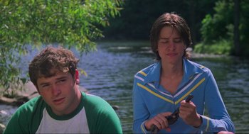 Movie still from “The Burning” (1981), directed by Tony Maylam – Two people sitting by a body of water; Medium shot, Low angle