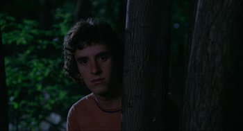 Movie still from “The Burning” (1981), directed by Tony Maylam – A man standing next to a tree in the dark; Medium shot, Low angle