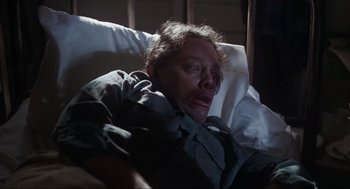Movie still from “The Burning” (1981), directed by Tony Maylam – A man with a bandaged face laying in a hospital bed; Close Up shot, High angle