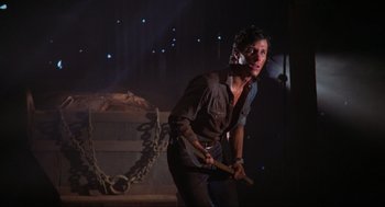 Movie still from “The Burning” (1981), directed by Tony Maylam – A man holding a wooden stick in his hand; Medium shot, Low angle