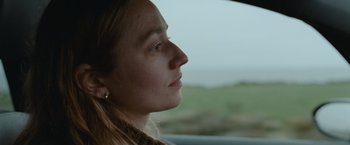 Movie still from “The Burning Sea” (2021), directed by John Andreas Andersen – A woman sitting in a car looking out the window; Close Up shot, Over the shoulder angle