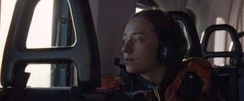 Movie still from “The Burning Sea” (2021), directed by John Andreas Andersen – A person wearing headphones and looking at a computer screen; Close Up shot, Low angle