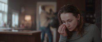 Movie still from “The Burning Sea” (2021), directed by John Andreas Andersen – A young woman holding her hand to her face; Close Up shot, Over the shoulder angle