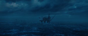 Movie still from “The Burning Sea” (2021), directed by John Andreas Andersen – An oil rig in the middle of the ocean under a cloudy sky; Extreme Wide shot, High angle