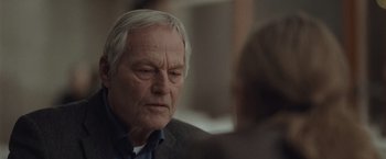 Movie still from “The Burning Sea” (2021), directed by John Andreas Andersen – An older man sitting in front of a woman; Close Up shot, Over the shoulder angle