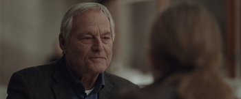 Movie still from “The Burning Sea” (2021), directed by John Andreas Andersen – An older man sitting in front of another man; Close Up shot, Over the shoulder angle