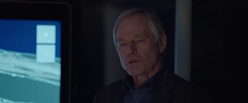 Movie still from “The Burning Sea” (2021), directed by John Andreas Andersen – An older man in a dark room looking at the camera; Close Up shot, Over the shoulder angle