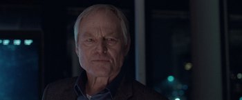 Movie still from “The Burning Sea” (2021), directed by John Andreas Andersen – An older man with a gray beard and a blue shirt; Close Up shot, Low angle