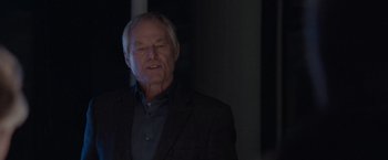 Movie still from “The Burning Sea” (2021), directed by John Andreas Andersen – An older man wearing a black jacket and a blue shirt; Close Up shot, Over the shoulder angle