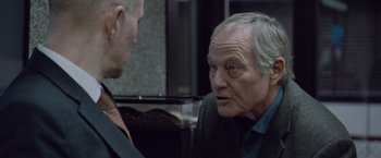 Movie still from “The Burning Sea” (2021), directed by John Andreas Andersen – A man in a suit talking to another man in a suit; Close Up shot, Over the shoulder angle