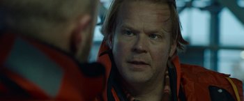 Movie still from “The Burning Sea” (2021), directed by John Andreas Andersen – A person wearing a jacket; Close Up shot, Over the shoulder angle