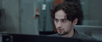 Movie still from “The Burning Sea” (2021), directed by John Andreas Andersen – A man with a beard is looking at a computer screen; Close Up shot, Over the shoulder angle