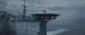 Movie still from “The Burning Sea” (2021), directed by John Andreas Andersen – A helicopter is flying over the ocean on a platform; Extreme Wide shot, High angle