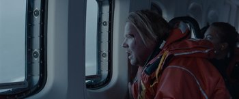 Movie still from “The Burning Sea” (2021), directed by John Andreas Andersen – A man in a red jacket looking out of a window; Medium shot, Over the shoulder angle