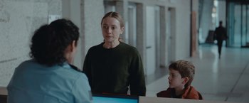 Movie still from “The Burning Sea” (2021), directed by John Andreas Andersen – A woman standing in front of two other people; Medium shot, Over the shoulder angle