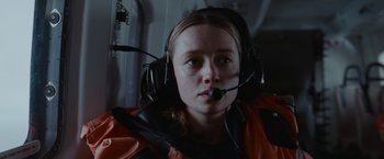 Movie still from “The Burning Sea” (2021), directed by John Andreas Andersen – A woman with a headset in a helicopter cockpit; Close Up shot, Low angle