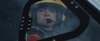 Movie still from “The Burning Sea” (2021), directed by John Andreas Andersen – A person in a helicopter with a helmet on; Close Up shot, Low angle