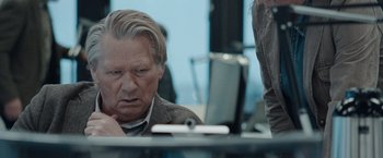 Movie still from “The Burning Sea” (2021), directed by John Andreas Andersen – An older man sitting in front of a cell phone; Close Up shot, Over the shoulder angle