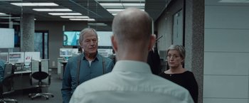 Movie still from “The Burning Sea” (2021), directed by John Andreas Andersen – Two men and a woman are standing in an office; Medium shot, Over the shoulder angle