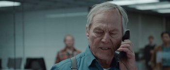 Movie still from “The Burning Sea” (2021), directed by John Andreas Andersen – An older man is talking on a cell phone; Close Up shot, Low angle