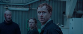 Movie still from “The Burning Sea” (2021), directed by John Andreas Andersen – A man and a woman standing next to each other in front of a building; Close Up shot, Over the shoulder angle