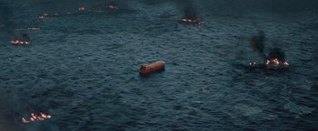 Movie still from “The Burning Sea” (2021), directed by John Andreas Andersen – An orange boat floating on top of a body of water; Extreme Wide shot, High angle