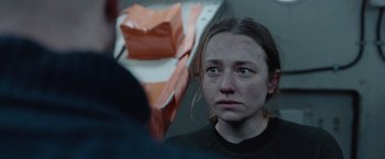 Movie still from “The Burning Sea” (2021), directed by John Andreas Andersen – A young woman looking sad in front of an orange bag; Close Up shot, Over the shoulder angle