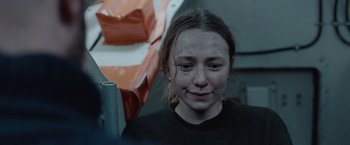 Movie still from “The Burning Sea” (2021), directed by John Andreas Andersen – A young girl with a black shirt and brown hair; Close Up shot, Over the shoulder angle