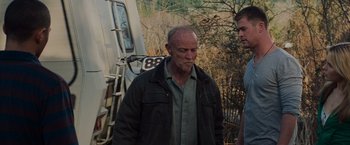 Movie still from “The Cabin in the Woods” (2011), directed by Drew Goddard – A man standing next to another man in front of a train; Medium shot, Low angle