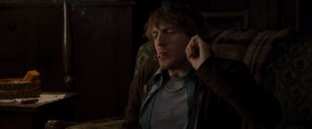 Movie still from “The Cabin in the Woods” (2011), directed by Drew Goddard – A man sitting on a couch smoking a cigarette; Medium shot, High angle