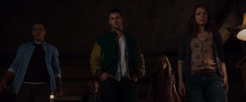 Movie still from “The Cabin in the Woods” (2011), directed by Drew Goddard – A man standing in front of two women in a room; Medium shot, Low angle