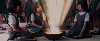 Movie still from “The Cabin in the Woods” (2011), directed by Drew Goddard – A young girl is sitting in front of a fire pit; Medium shot, High angle