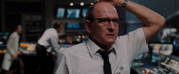 Movie still from “The Cabin in the Woods” (2011), directed by Drew Goddard – A man with glasses and a tie is looking at the camera; Close Up shot, Low angle