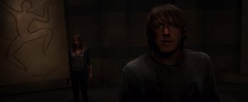 Movie still from “The Cabin in the Woods” (2011), directed by Drew Goddard – A man and a woman standing in a dark room; Medium shot, Over the shoulder angle
