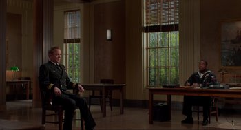 Movie still from “The Caine Mutiny Court-Martial” (2023), directed by William Friedkin – A man sitting on a chair next to a window; Wide shot, Over the shoulder angle