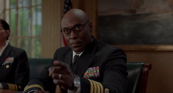 Movie still from “The Caine Mutiny Court-Martial” (2023), directed by William Friedkin – A man in a uniform sitting in front of an american flag; Close Up shot, Low angle